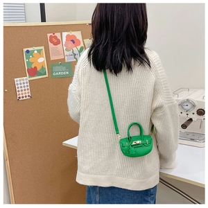 Détail d'un mini sac Kelly vert avec breloque étoile et fermoir métallique doré chic