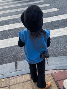 Fillette portant un mini sac bandoulière en cuir noir avec gilet denim et chapeau tricot