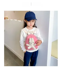 Pink mini toddler backpack featuring a 3D plush bunny and white woven straps on a child