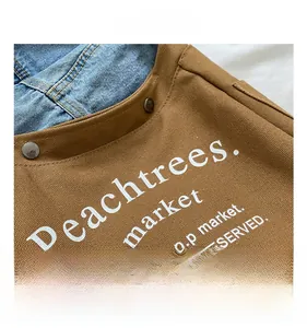 Detail of brown canvas kid crossbody bag with Peachtrees market logo and rivets