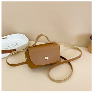 Detailed close-up of brown faux leather mini bag with gold magnetic buckle and top handle