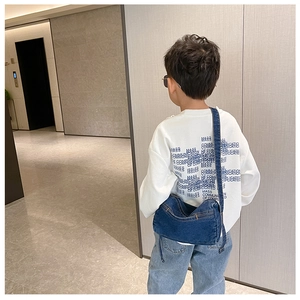Close-up of kids denim crossbody bag styled with a white graphic letter sweatshirt