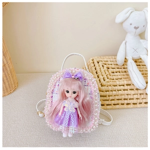 Close-up of white mini backpack with doll charm, pearls, and soft velvet textures