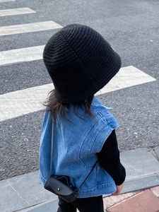 Fillette avec chapeau cloche en tricot noir et petit sac à bandoulière en extérieur