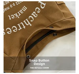 Detail showing the snap button closure and fabric texture of the canvas crossbody bag