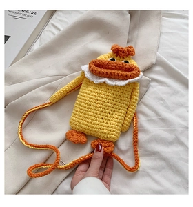 Close-up of handmade crochet duck crossbody bag with lace detail and woven strap
