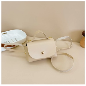 Detail view of mini beige PU leather crossbody bag with gold snap and rivet accents