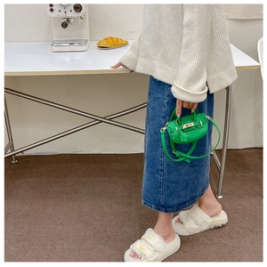 Détail d'un mini sac à bandoulière en cuir vert grainé porté comme accessoire de mode