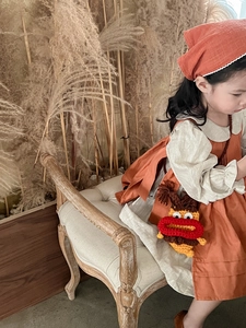 Détail d'un petit sac monstre en crochet sur une robe vintage en lin pour enfant