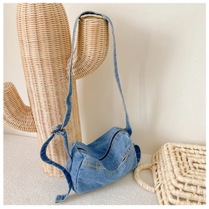 Detail of blue denim crossbody bag with orange stitching on a cactus stand