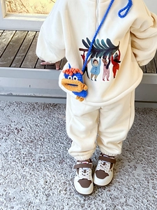 Détail d'un enfant portant un sac bandoulière monstre en crochet bleu et jogging