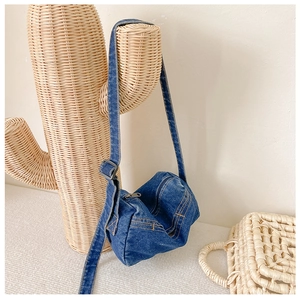 Detail of blue denim crossbody bag with yellow contrast stitching and adjustable strap
