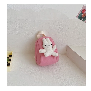 Close-up of pink canvas backpack with a white plush bunny and fabric strap handles