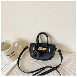 Détail d'un mini sac demi-lune noir avec fermoir doré et breloques étoiles sur tissu