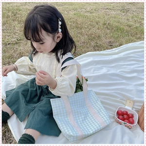 Detailed outdoor shot of a green and white checkered canvas tote bag for girls