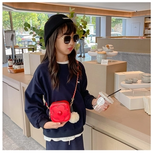 Fille portant un sac à bandoulière fleur rouge avec pompon blanc et sweat-shirt bleu marine