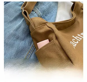Detail of canvas shoulder bag showing side pocket, strap buckle and stitching