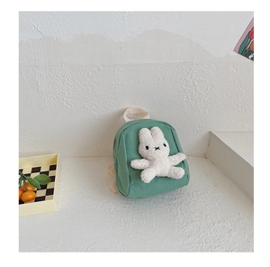 Detail of green canvas toddler backpack featuring a white plush 3D bunny character