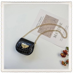 Detailed macro view of black crocodile texture mini bag with gold chain and latch lock
