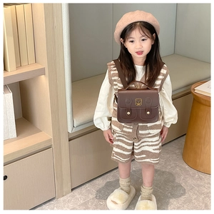 Detail view of a vintage dark brown PU leather children backpack with gold bear logo