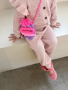 Détail du sac bandoulière monstre en tricot pour enfants avec pompons roses et visage cartoon