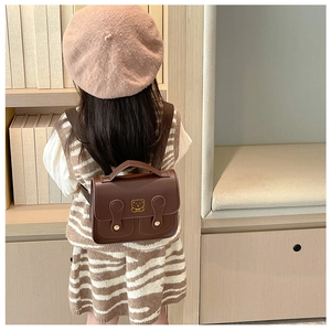 Detailed view of kids vintage brown satchel featuring golden bear logo and buckles