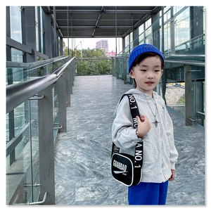 Detail of kids black crossbody sport bag with white text print and wide shoulder strap