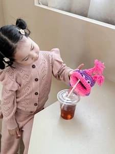 Détail d'un petit sac monstre en crochet rose tenu par une enfant sous une lumière douce