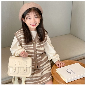Detail of a cute beige mini bag with embossed bear pattern on a stylish kids outfit