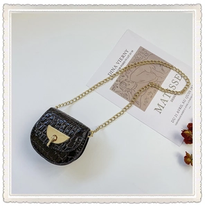Detail of black faux crocodile leather mini saddle bag with gold chain and metal lock