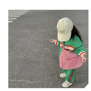 Pink canvas crossbody bag for kids styled with casual green tracksuit on the street