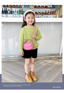 Pink girl's mini handbag with round handle and detachable strap on green knitwear