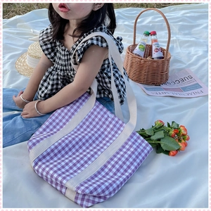 Detail of children's purple gingham canvas tote bag in a sunny outdoor picnic setting