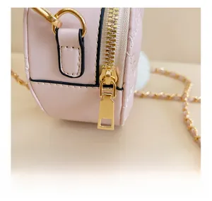 Close-up of smooth golden zipper and quilted leather texture on girl's chain bag