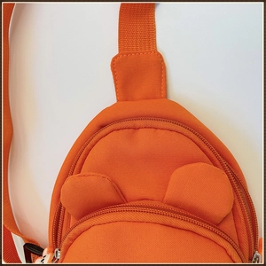 Gros plan d'un sac de poitrine orange pour enfants avec oreilles et pendentif cartoon