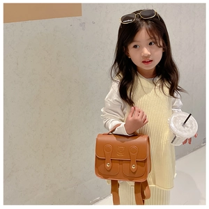 Toddler brown faux leather backpack with bear embossing and handle shown on model
