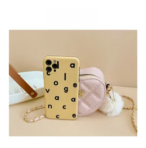 Pink heart-shaped mini bag with gold chain showing compact size compared to a phone