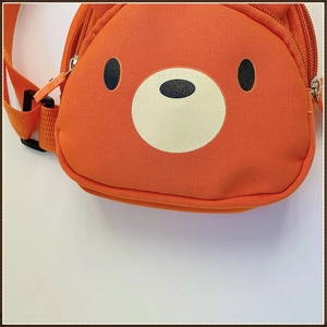 Détail du sac à bandoulière ours orange en toile avec deux compartiments zippés