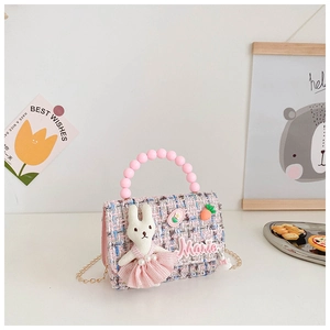 Détail d'un mini sac en tweed avec poignée perle, chaîne dorée et décoration de lapin mignon