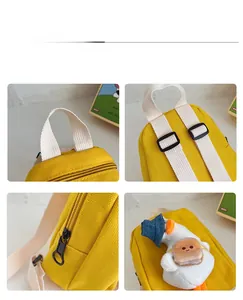 Detail display of yellow canvas mini backpack with cute plush duck and strap buckles