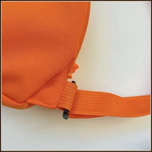 Gros plan d'un sac en toile orange montrant les coutures renforcées et la boucle réglable