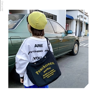 Close-up of black canvas crossbody bag for kids with yellow letter print decoration