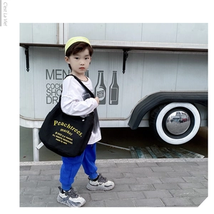 Kids streetwear style featuring a black canvas crossbody bag with yellow letter print