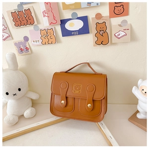 Detailed view of brown PU leather children bag with cute embroidered bear and metal buckles