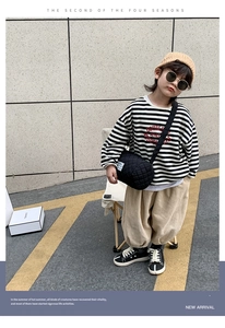 Detailed view of children's black quilted crossbody bucket bag with casual streetwear outfit