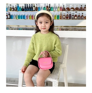 Detail of pink leather girl's handbag with gold buckle and knit sweater outfit
