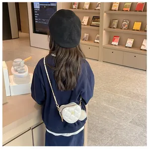 Detailed view of girls heart-shaped quilted mini crossbody bag with gold chain strap