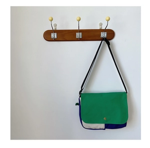 Détail du sac bandoulière en toile multicolore avec rabat vert et base bleu foncé