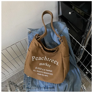 Close-up of brown canvas tote with letter print inside a metal shopping cart