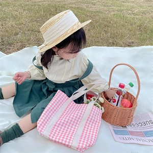 Pink checkered canvas tote bag for girls on a picnic blanket with natural outdoor scenery